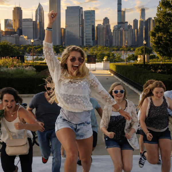 Excited tour group racing up steps toward the camera with the Chicago skyline glowing at sunset.
