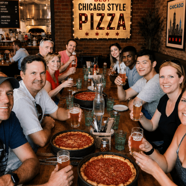 Food tour group raising beers around deep dish pizzas at a Chicago-style pizza restaurant.