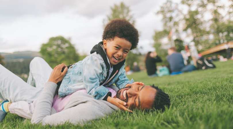 dad and son playing in grass at park